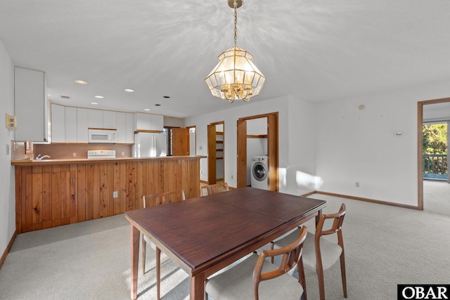 dining area with washer / dryer, light carpet, a notable chandelier, and baseboards