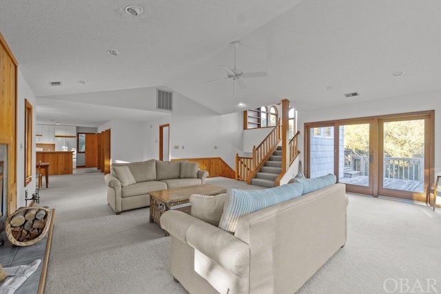 living room with stairs, lofted ceiling, visible vents, and light colored carpet