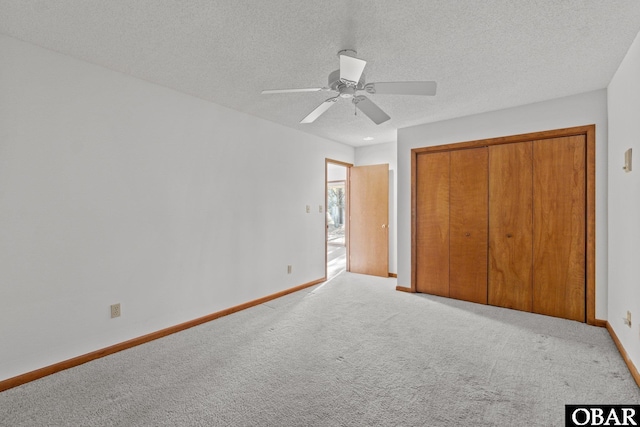 unfurnished bedroom featuring baseboards, a textured ceiling, a closet, and light colored carpet