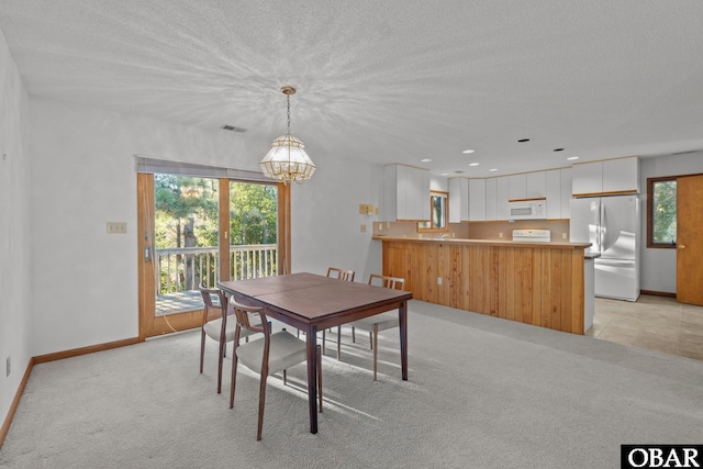 dining space featuring light carpet, baseboards, visible vents, an inviting chandelier, and a textured ceiling