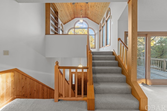 stairway featuring carpet floors, wooden ceiling, plenty of natural light, and wooden walls