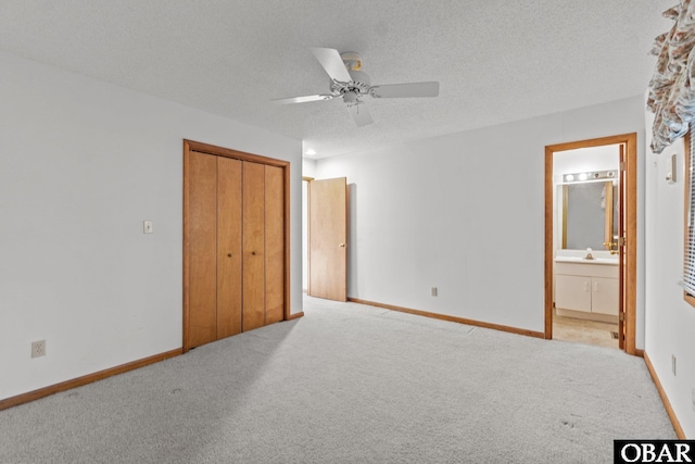 unfurnished bedroom featuring a closet, light carpet, a textured ceiling, and baseboards