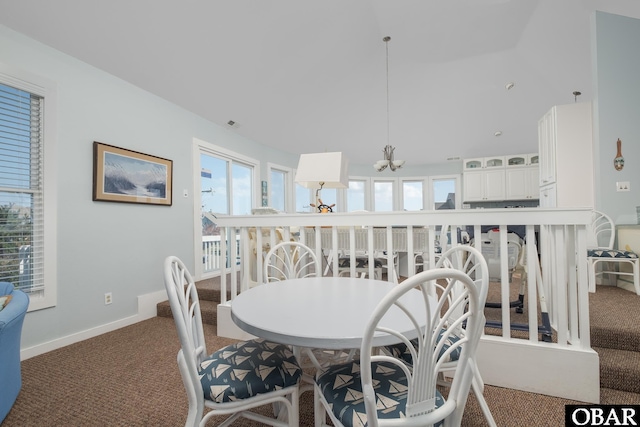 carpeted dining room featuring a chandelier and baseboards