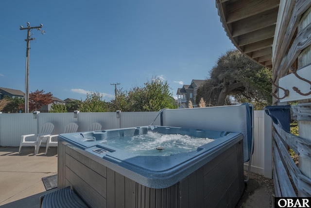 view of patio / terrace with a hot tub and fence