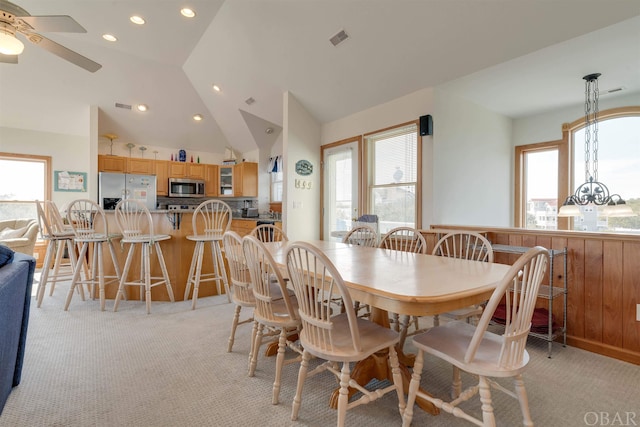 dining room with light colored carpet, a wealth of natural light, visible vents, and lofted ceiling