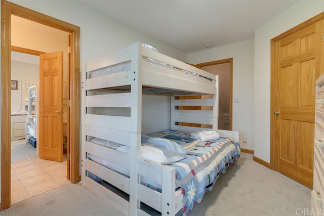 bedroom with light carpet, light tile patterned flooring, and baseboards