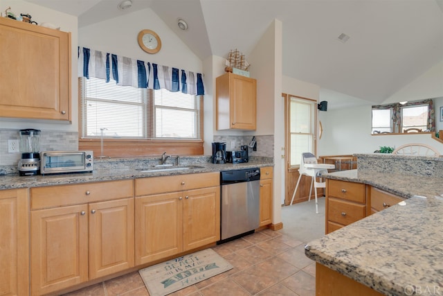 kitchen featuring light stone counters, lofted ceiling, light brown cabinets, a sink, and dishwasher