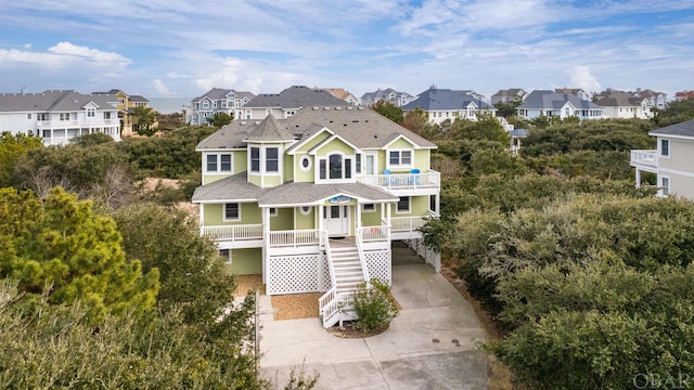 view of front of house featuring a residential view, covered porch, driveway, and stairs