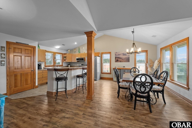 dining space with lofted ceiling, wood finished floors, decorative columns, and a notable chandelier