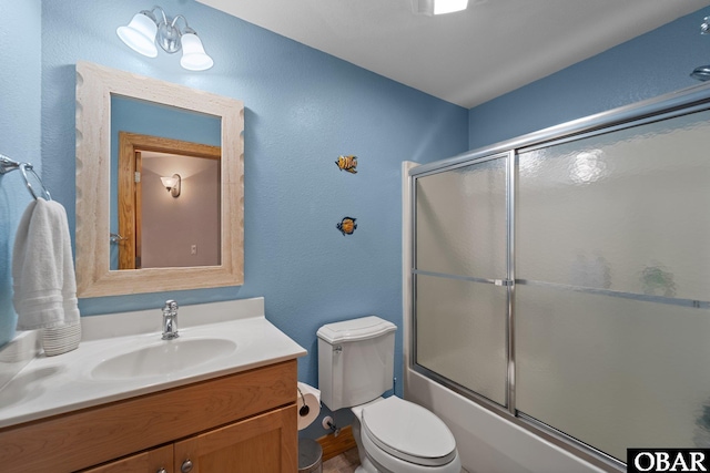 bathroom featuring enclosed tub / shower combo, vanity, and toilet