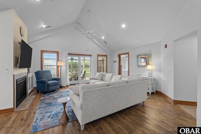 living room with baseboards, dark wood finished floors, a tile fireplace, ceiling fan, and high vaulted ceiling