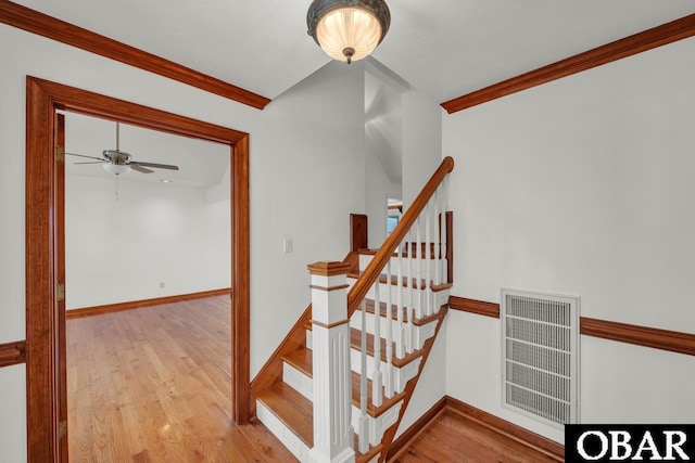 stairs featuring ceiling fan, visible vents, wood finished floors, baseboards, and ornamental molding