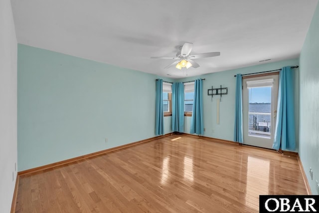 spare room featuring baseboards, plenty of natural light, a ceiling fan, and wood finished floors