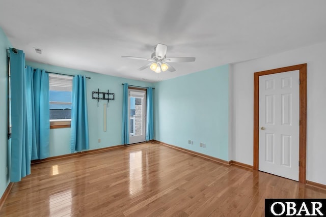 unfurnished bedroom with baseboards, ceiling fan, multiple windows, and wood finished floors