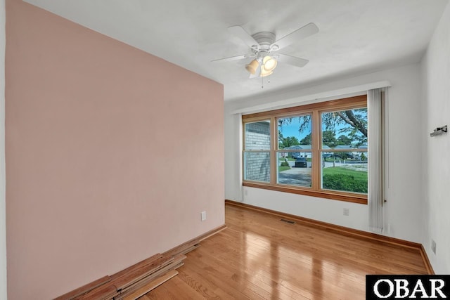 unfurnished room with baseboards, a ceiling fan, light wood-style floors, and visible vents