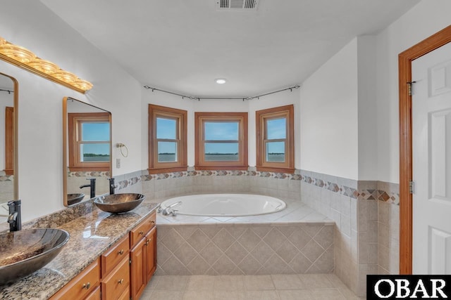 full bath featuring tile patterned flooring, a sink, a bath, and double vanity