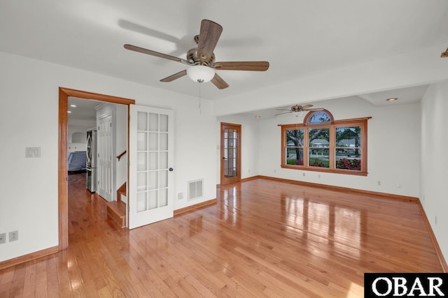 empty room with french doors, a ceiling fan, visible vents, baseboards, and light wood-style flooring