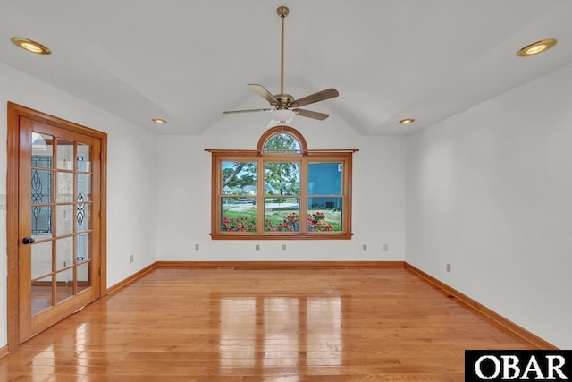 empty room with baseboards, light wood finished floors, ceiling fan, and vaulted ceiling