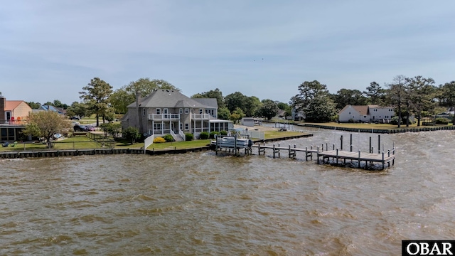 dock area with a water view, a yard, and a balcony