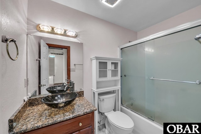 bathroom with vanity, combined bath / shower with glass door, and toilet