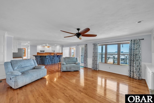 living room featuring crown molding, ceiling fan, recessed lighting, a wainscoted wall, and light wood-style flooring