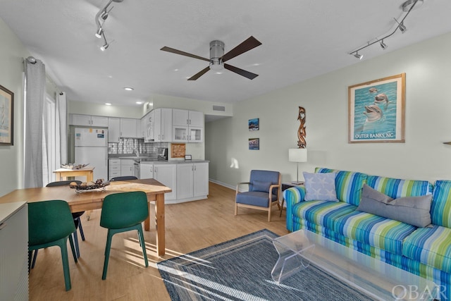 living area with ceiling fan, light wood finished floors, rail lighting, and visible vents