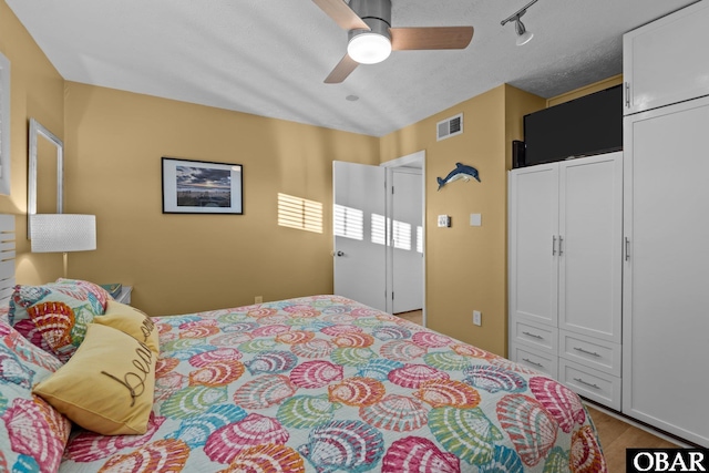 bedroom featuring a ceiling fan, a closet, visible vents, and a textured ceiling