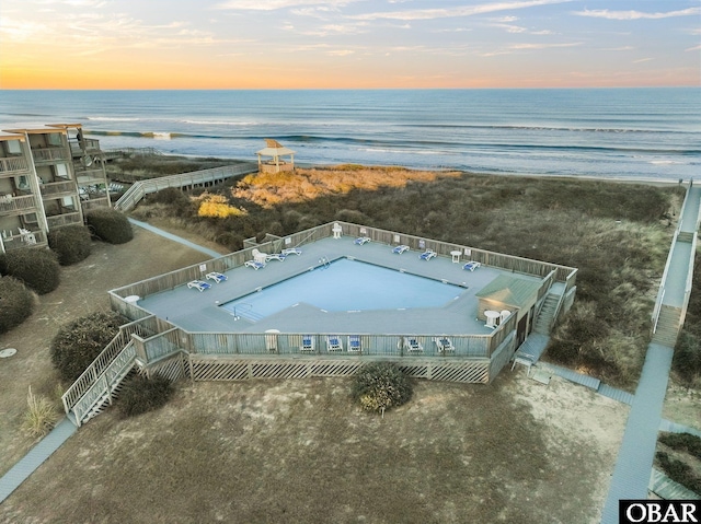 aerial view at dusk featuring a beach view and a water view