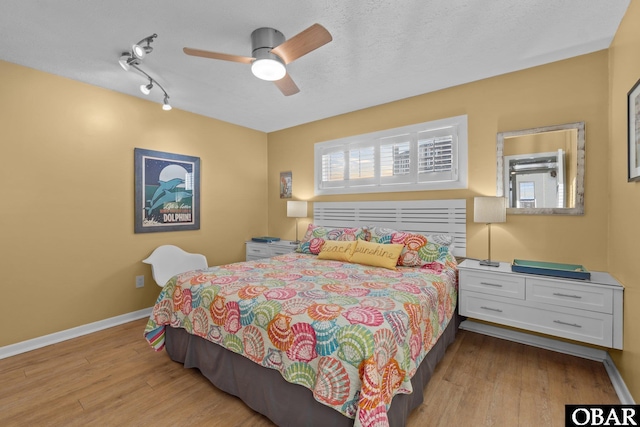 bedroom featuring a ceiling fan, multiple windows, light wood-style flooring, and baseboards