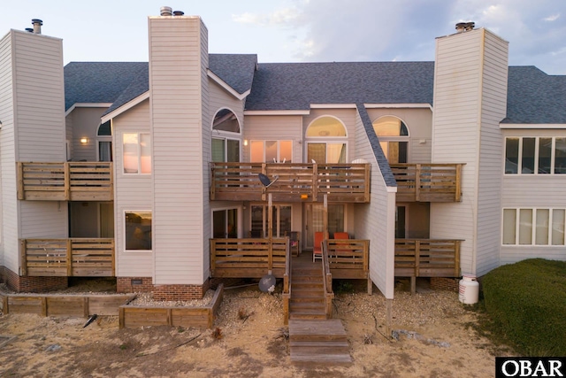 rear view of house featuring crawl space, a chimney, and roof with shingles