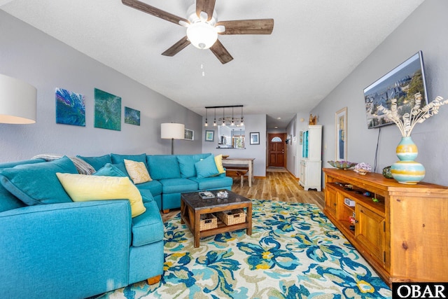 living room featuring ceiling fan, a textured ceiling, wood finished floors, and rail lighting