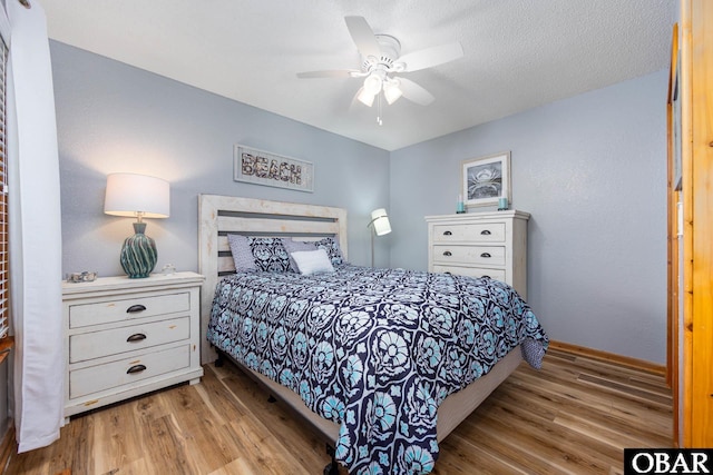 bedroom featuring ceiling fan, a textured ceiling, baseboards, and wood finished floors