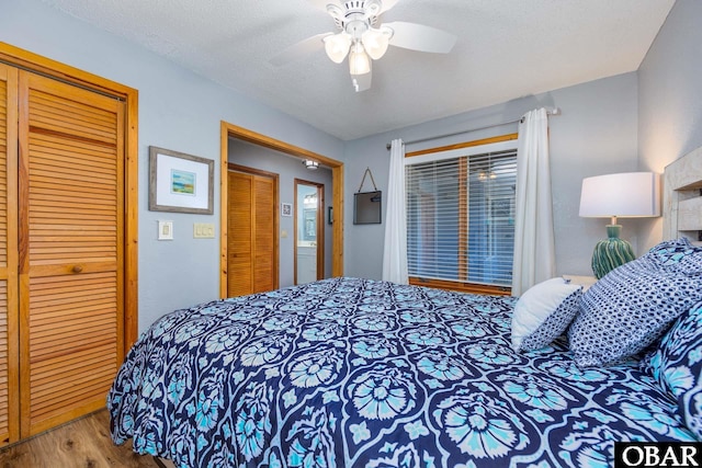 bedroom featuring a textured ceiling, a closet, wood finished floors, and a ceiling fan