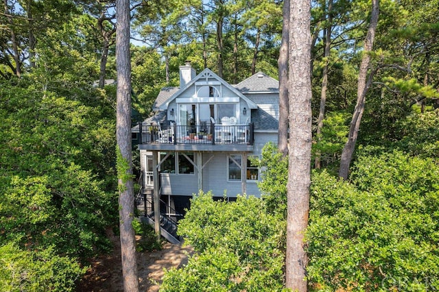 back of house featuring a deck, roof with shingles, stairway, and a chimney