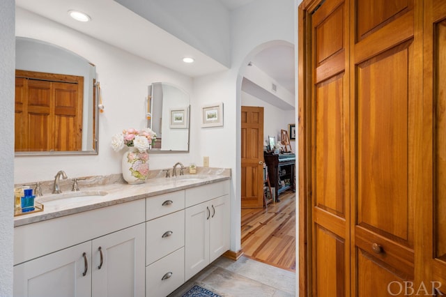 bathroom with a sink, double vanity, a closet, and recessed lighting