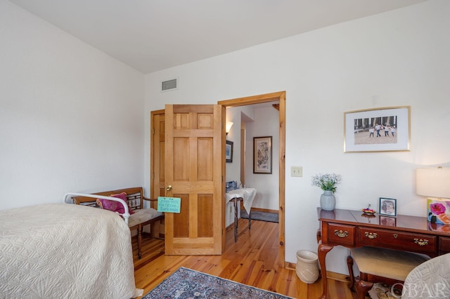 bedroom with visible vents, light wood-style flooring, and baseboards