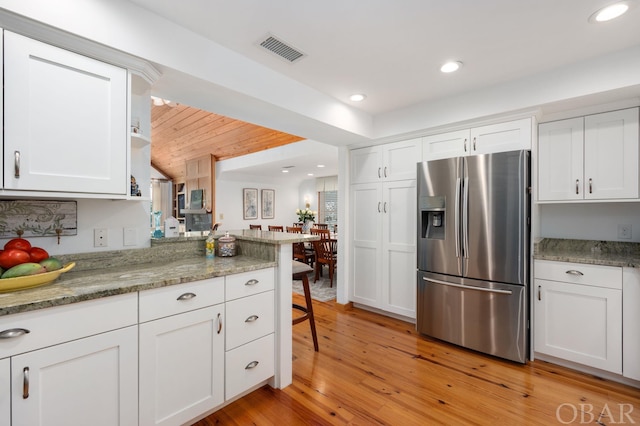 kitchen featuring stainless steel refrigerator with ice dispenser, recessed lighting, visible vents, light wood-style flooring, and white cabinetry