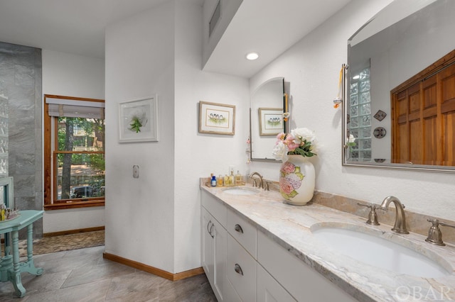 bathroom featuring a sink, baseboards, and double vanity