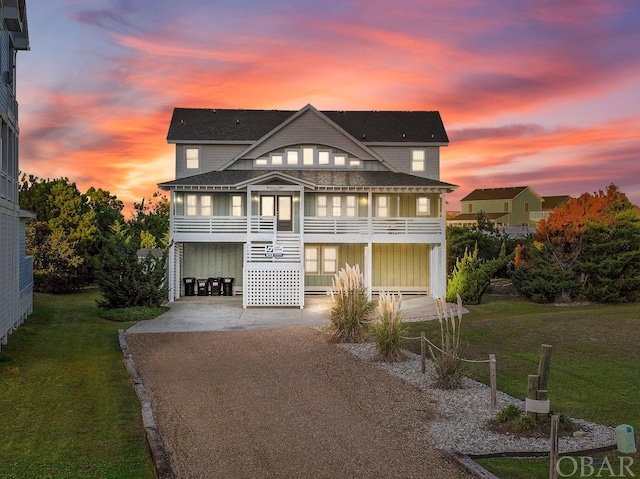 view of front of house with driveway, a lawn, a balcony, stairway, and a carport