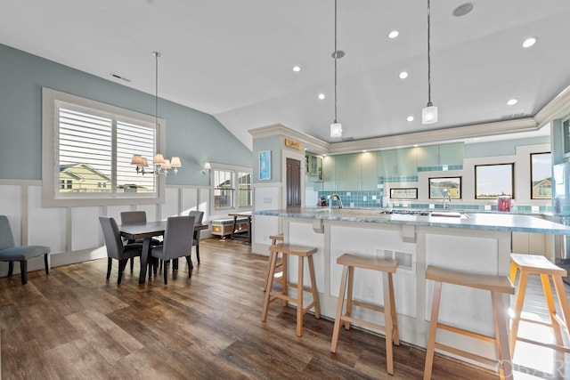 kitchen featuring a kitchen breakfast bar, wainscoting, light stone countertops, and pendant lighting