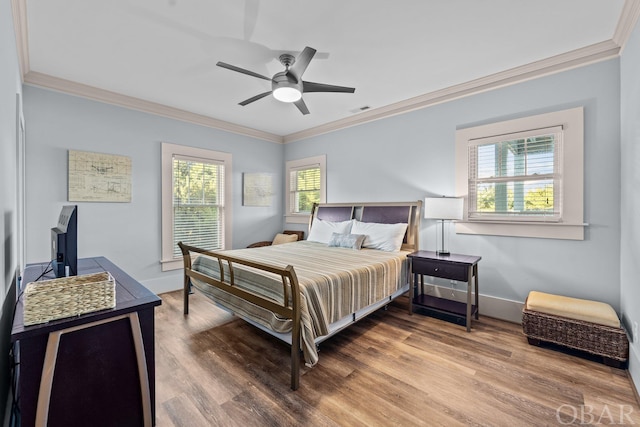 bedroom with crown molding, wood finished floors, visible vents, and baseboards