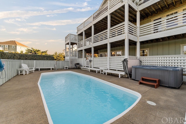 pool at dusk with a fenced in pool, a patio area, fence, and a hot tub