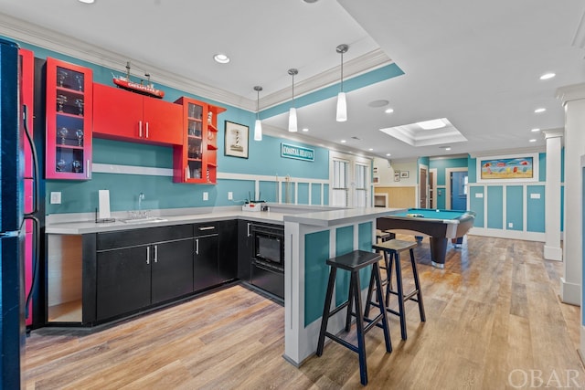 kitchen with a breakfast bar, light countertops, crown molding, dark cabinetry, and a sink