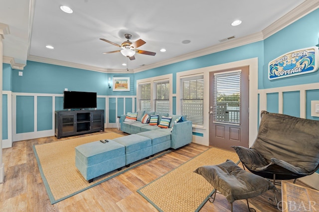 living room with crown molding, a decorative wall, and wood finished floors