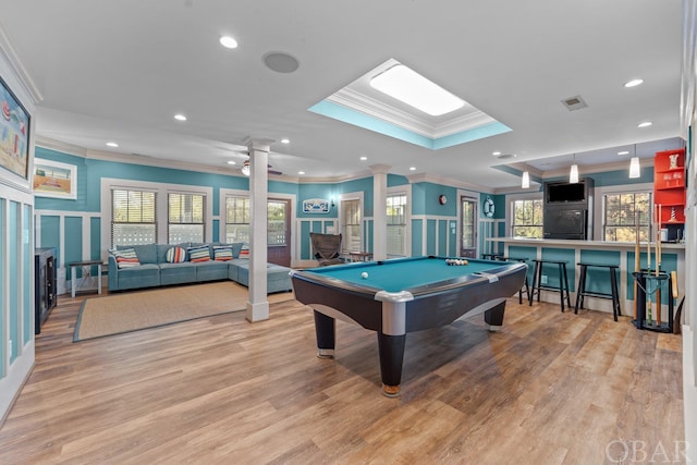 recreation room featuring a wealth of natural light, visible vents, decorative columns, and light wood finished floors