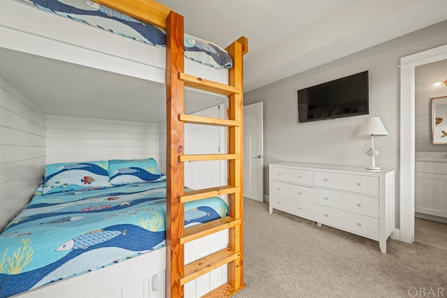 bedroom featuring light carpet and wooden walls