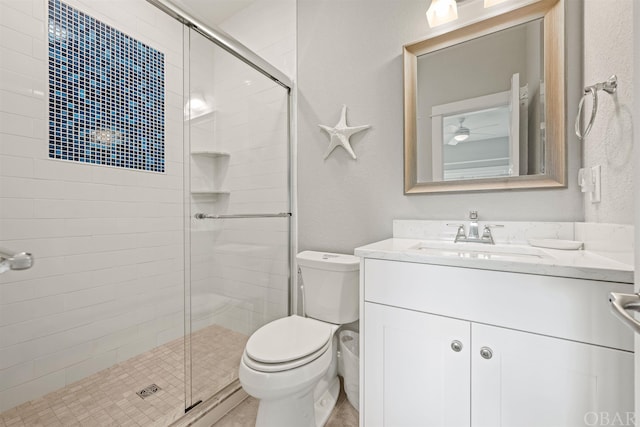 bathroom featuring vanity, a shower stall, and toilet