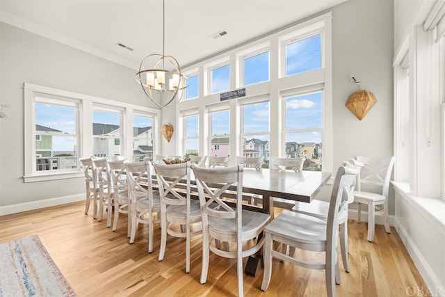 dining space featuring baseboards, visible vents, a notable chandelier, and light wood finished floors