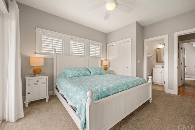 bedroom with ensuite bath, baseboards, a closet, and light colored carpet