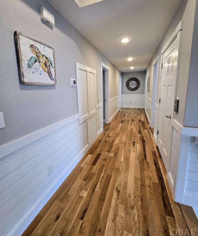 hallway featuring a wainscoted wall and wood finished floors